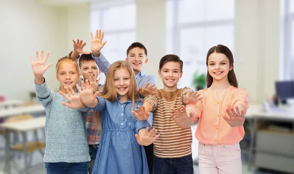 Estudantes felizes acenando as mãos na escola — Fotografia de Stock