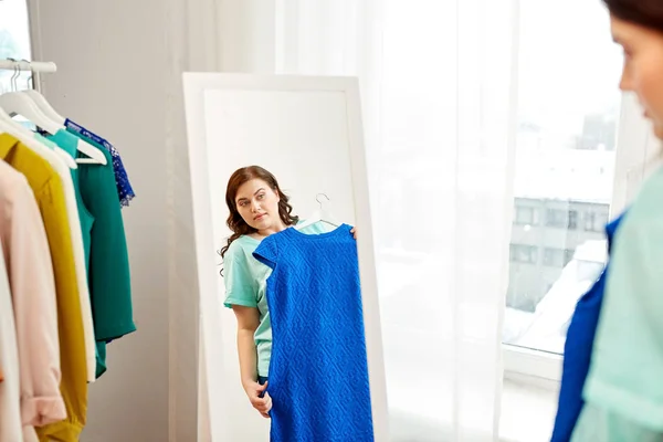 Zamyšlený plus velikost ženy s modré šaty na zrcadlo — Stock fotografie
