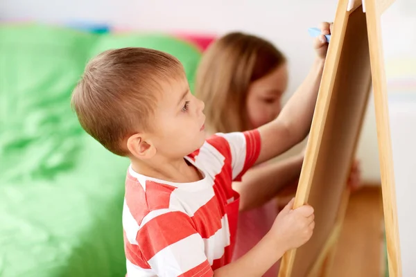 Happy kids drawing on chalk board at home — Stock Photo, Image