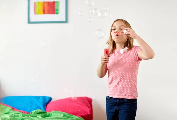 Mädchen pustet zu Hause Seifenblasen — Stockfoto