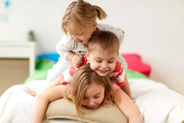 Niños pequeños felices divirtiéndose en la cama en casa — Foto de Stock