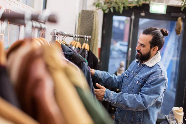 Мужчина выбирает одежду в магазине винтажной одежды — стоковое фото