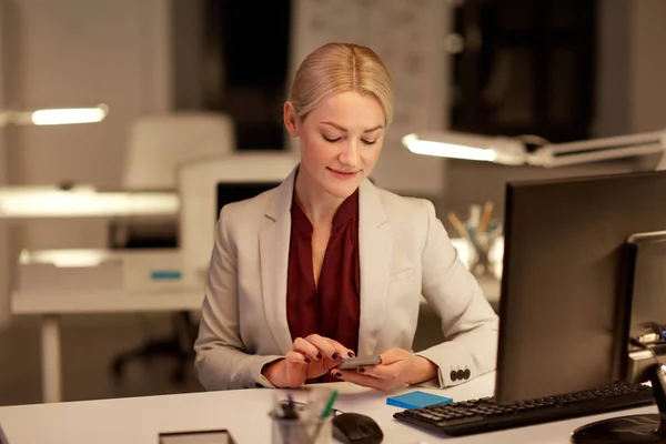 Mujer de negocios con teléfono inteligente en la oficina de noche — Foto de Stock