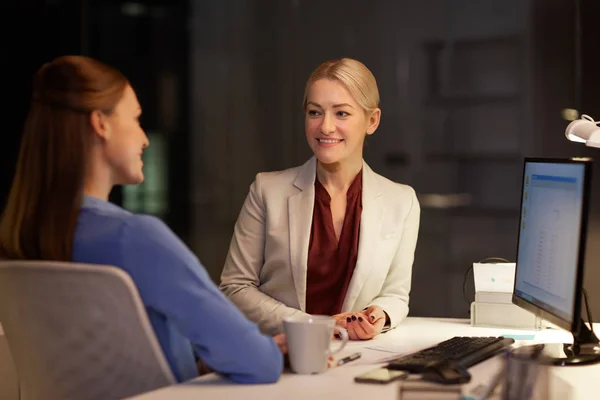 Mujeres de negocios felices hablando hasta tarde en la oficina de noche — Foto de Stock