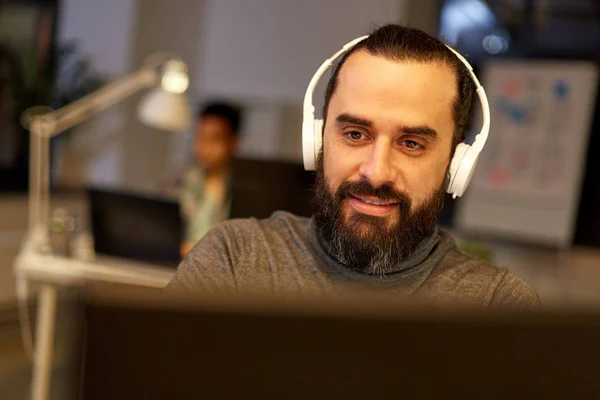 Homme créatif avec écouteurs travaillant au bureau — Photo