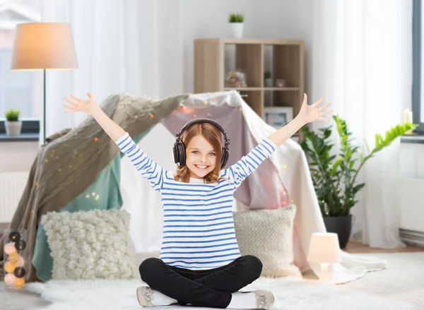 Jente med hodetelefoner som hører på musikk hjemme – stockfoto