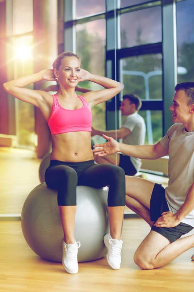 Uśmiechnięty mężczyzna i kobieta z piłka ćwiczenia w siłowni — Zdjęcie stockowe