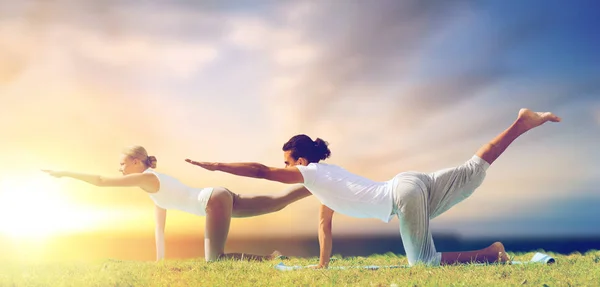 Coppia rendendo yoga bilanciamento tavolo posa all'aperto — Foto Stock