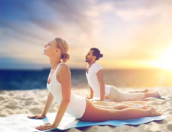 Pareja haciendo yoga y cobra pose en la playa — Foto de Stock
