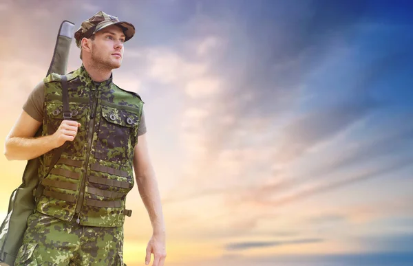 Young soldier or hunter with gun over sky — Stock Photo, Image