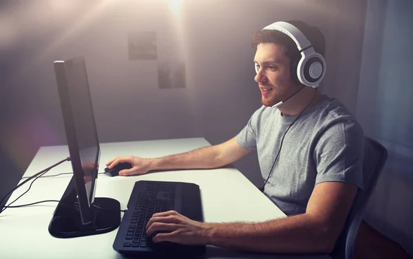 Hombre en auriculares jugando videojuego de ordenador en casa — Foto de Stock