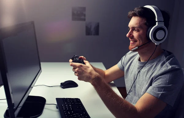 Hombre en auriculares jugando videojuego de ordenador en casa — Foto de Stock