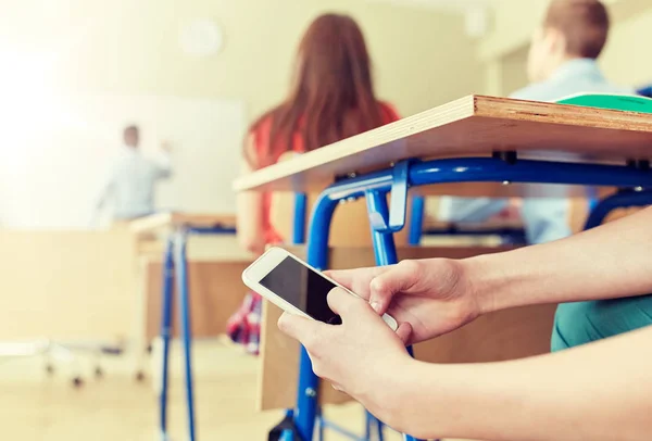 Estudiante chico con teléfono inteligente mensajes de texto en la escuela —  Fotos de Stock