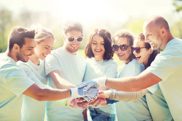 Group of volunteers putting hands on top in park — Stock Photo, Image