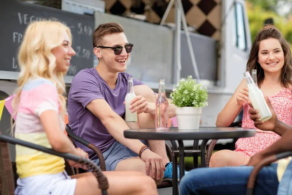 Friends with drinks sitting at table at food truck — Stock Photo, Image