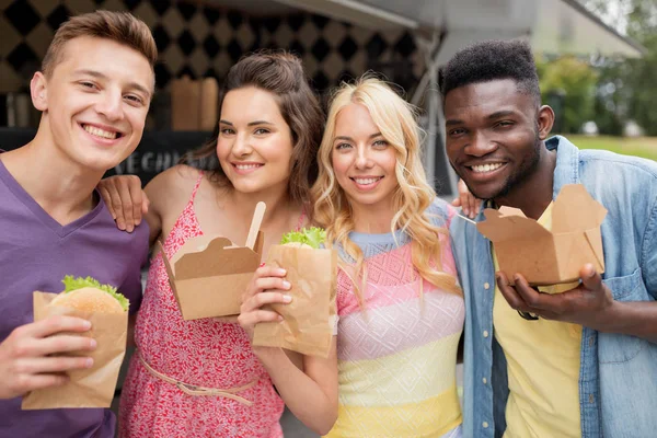 Amigos felizes com wok e hambúrguer no caminhão de alimentos — Fotografia de Stock