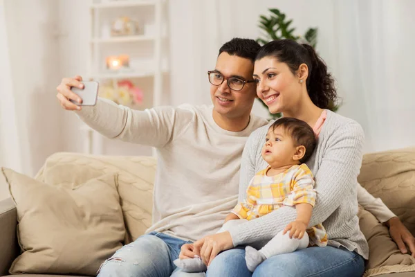 Mãe e pai com bebê tomando selfie em casa — Fotografia de Stock