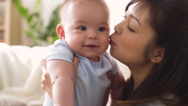 Feliz jovem mãe beijando bebê em casa — Vídeo de Stock
