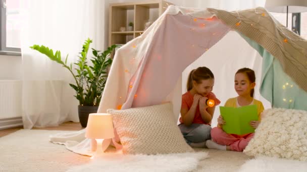 Niñas felices leyendo libro en tienda de campaña para niños en casa — Vídeos de Stock