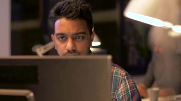 Креативний чоловік з комп'ютером, що працює в нічному офісі — стокове відео