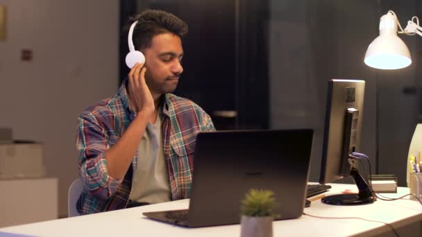 Hombre creativo con auriculares trabajando en la oficina — Vídeos de Stock