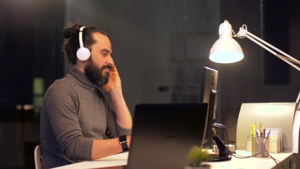 Креативный человек с наушниками работает в офисе — стоковое видео