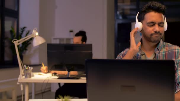 Креативний чоловік з навушниками, що працюють в офісі — стокове відео