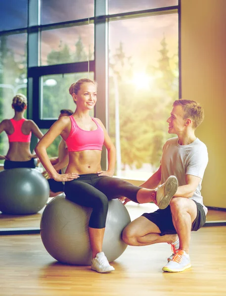 Sonriente hombre y mujer con bola de ejercicio en el gimnasio —  Fotos de Stock