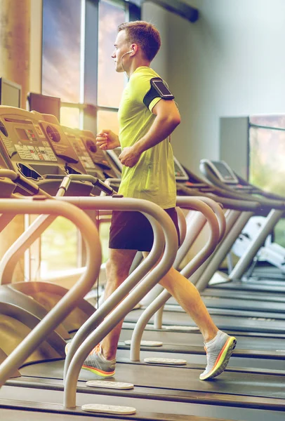 Man met smartphone uitoefenen op loopband in de sportschool — Stockfoto