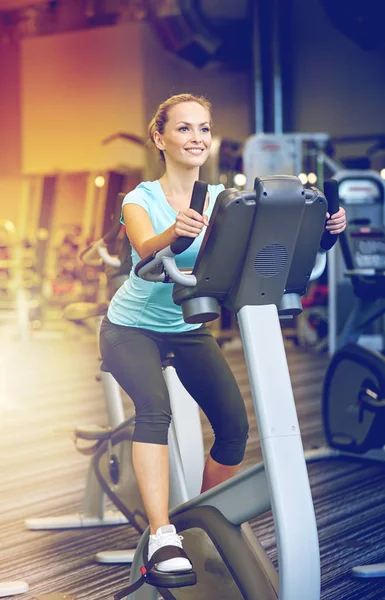 Mujer sonriente haciendo ejercicio en bicicleta estática en el gimnasio — Foto de Stock