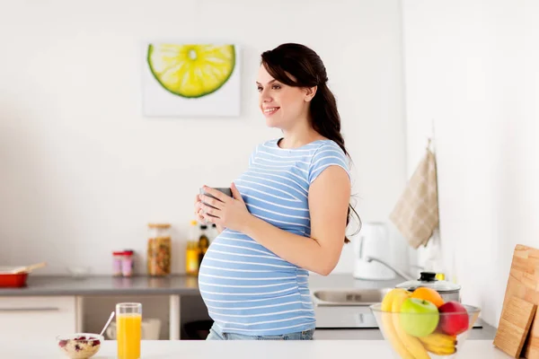 Mutfakta fincanı olan mutlu hamile bir kadın. — Stok fotoğraf