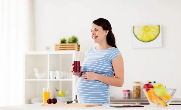 Feliz embarazada bebiendo jugo en casa —  Fotos de Stock