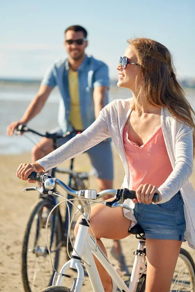 海辺で自転車に乗って幸せな若いカップル — ストック写真