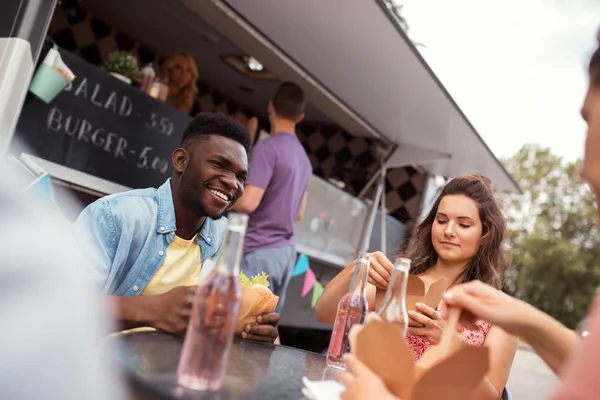 Amis heureux avec des boissons manger au camion de nourriture — Photo