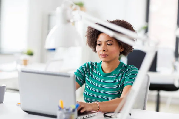 Mujer africana con computadora portátil en la oficina — Foto de Stock