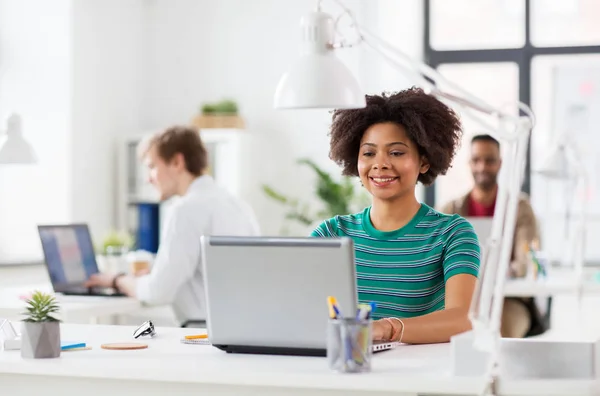 Mujer africana feliz con ordenador portátil en la oficina —  Fotos de Stock