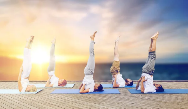 Mensen doen yoga shoulderstand op mat buitenshuis — Stockfoto