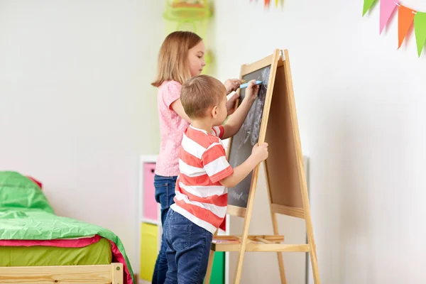 Happy kids drawing on chalk board at home — Stock Photo, Image