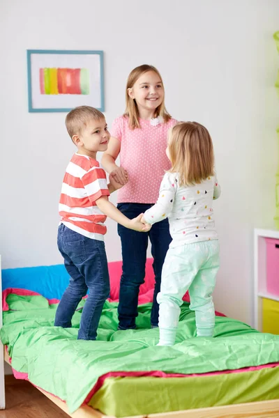 Glada små barn hoppa på sängen hemma — Stockfoto