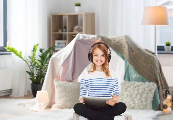 Menina com fones de ouvido e tablet pc em casa — Fotografia de Stock