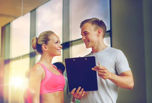 Lächelnde junge Frau mit Personal Trainer im Fitnessstudio — Stockfoto