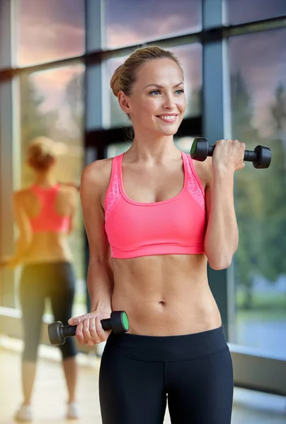 Young sporty woman with dumbbells flexing biceps — Stock Photo, Image