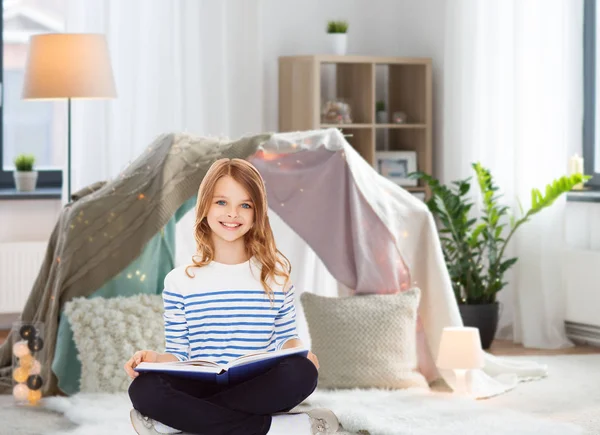 Happy smiling girl reading book at home Stock Picture