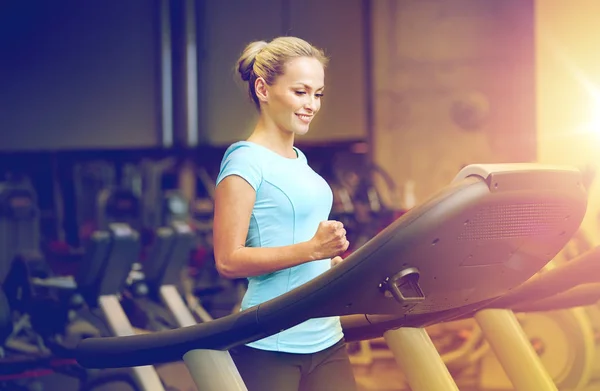 Улыбающаяся женщина, упражняющаяся на беговой дорожке в спортзале — стоковое фото