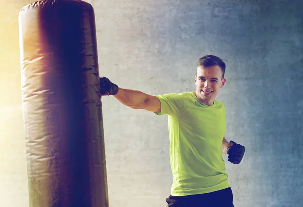 Young man in gloves boxing with punching bag — Stock Photo, Image