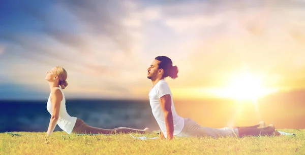 Pareja haciendo yoga cobra pose al aire libre —  Fotos de Stock