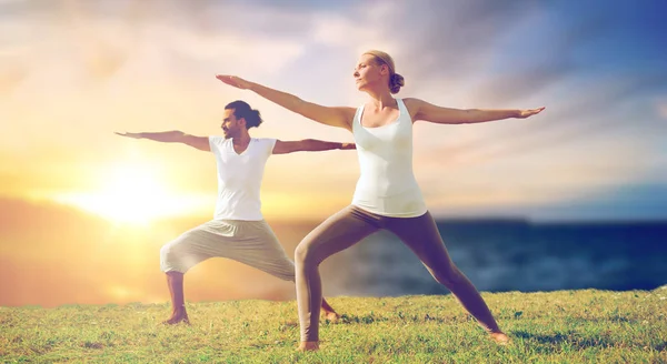 Coppia rendendo yoga guerriero posa all'aperto — Foto Stock