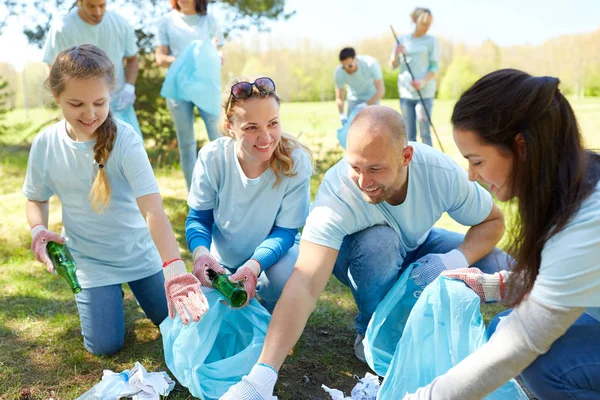 Vrijwilligers met vuilniszakken schoonmaak park — Stockfoto