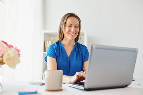 Mujer feliz con el ordenador portátil que trabaja en casa u oficina — Foto de Stock