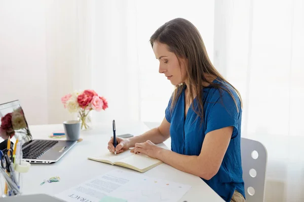 Kvinnan skriver till anteckningsboken på kontor — Stockfoto